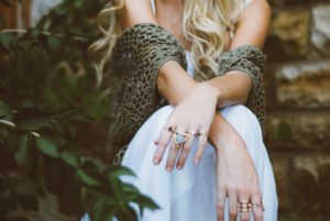 a lady with rings and a woven sweater