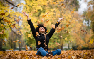 Joyous teen playing with dry maple leaves